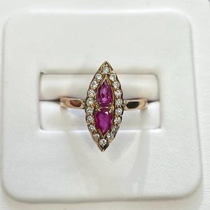 May include: A gold ring with a pear-shaped ruby surrounded by a halo of diamonds.