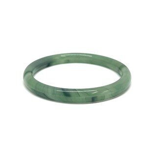 May include: A round, jade green bangle bracelet. The bracelet is a solid, smooth band with variations in the green color. The bangle is set against a white background.