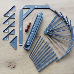 Könnte beinhalten: Eine Sammlung grauer Holzbearbeitungswerkzeuge, darunter ein 20 cm Winkel, ein Lineal und mehrere abgewinkelte Teile. Der Text "Cat Carry Handcraft" ist auf dem Winkel sichtbar. Ein kleiner Ahle mit rotem Griff ist ebenfalls vorhanden.