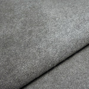 May include: Close-up of a gray textured leather fabric. The fabric has a slightly rough surface and a subtle sheen.