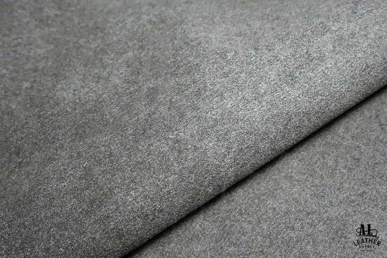 May include: Close-up of a gray textured leather fabric. The fabric has a slightly rough surface and a subtle sheen.