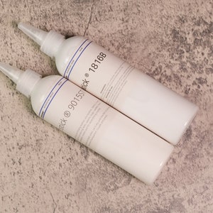 May include: Two white bottles of adhesive with blue labels and the text "Stick @ 90155T Stick @ 1816B".