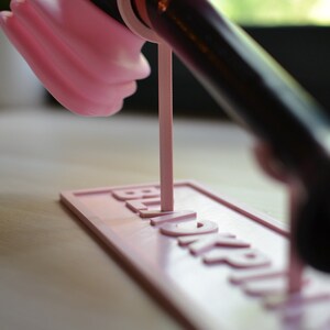 May include: A pink and black hair dryer stand with the word "Remarkable" printed on the base.