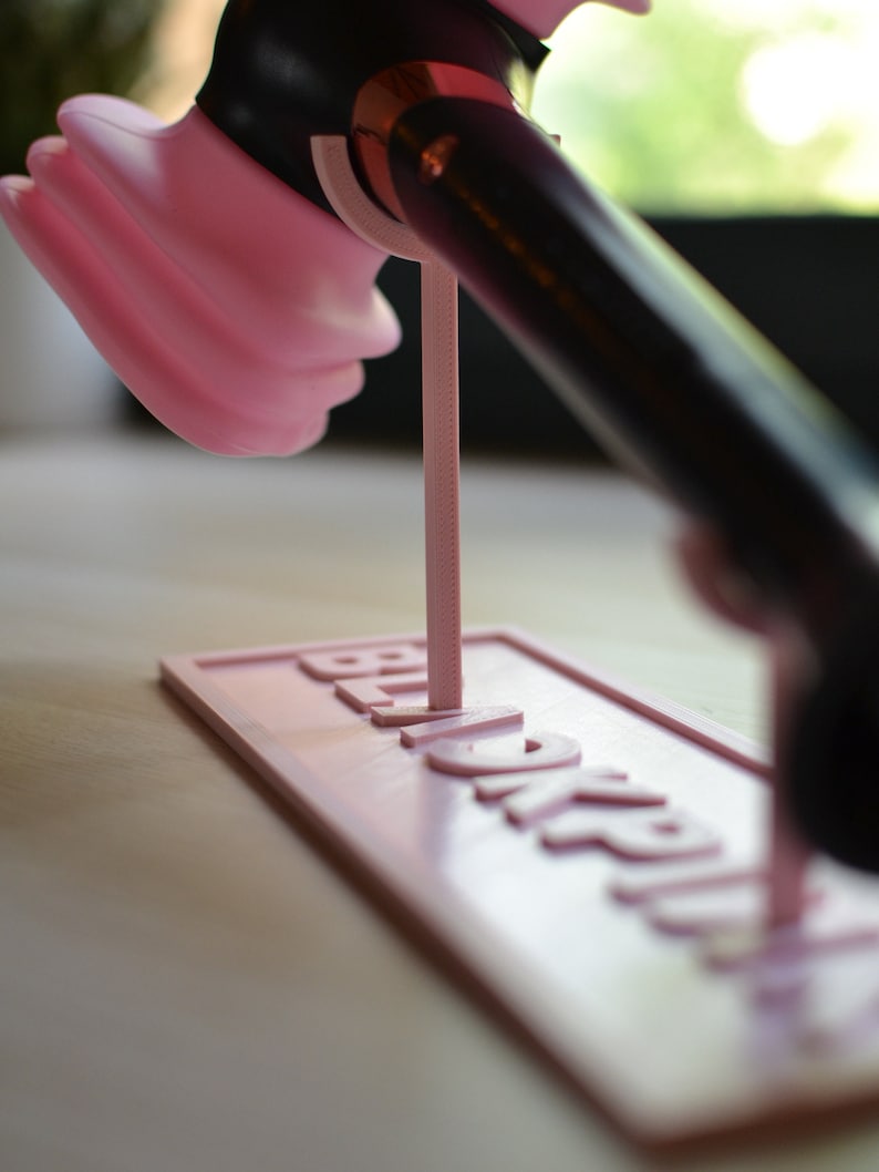 May include: A pink and black hair dryer stand with the word "Remarkable" printed on the base.