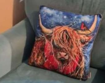 May include: A blue armchair with a throw pillow featuring a highland cow with a snowy background. The pillow has a red and white plaid pattern around the cow's neck.