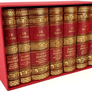 May include: A set of seven hardback books in a red box. The books are all the same size and have gold lettering on the spines. The titles of the books are "Harry Potter and the Philosopher's Stone", "Harry Potter and the Chamber of Secrets", "Harry Potter and the Prisoner of Azkaban", "Harry Potter and the Goblet of Fire", "Harry Potter and the Order of the Phoenix", "Harry Potter and the Half-Blood Prince", and "Harry Potter and the Deathly Hallows".