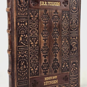 Op de afbeelding: Een ledergebonden boek, "Beren and Lúthien" van J.R.R. Tolkien. De bruine kaft heeft reliëf ontwerpen en namen van personages. De titel en auteur zijn in goudkleurige letters. De rug van het boek is zichtbaar.