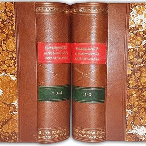 May include: Two antique books with brown leather covers and marbled endpapers. The spines are brown with red and green labels. Gold decorative elements are present on the spines. The books are open, displaying the pages.