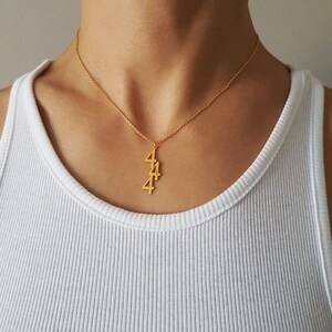 May include: Gold necklace with a pendant featuring the number 4 repeated three times.
