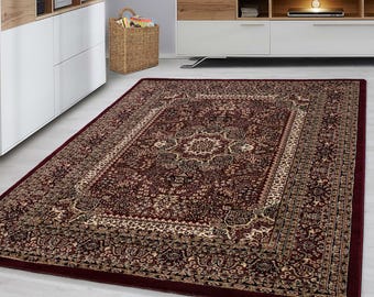 May include: A rectangular, ornate area rug with a deep burgundy border and a central design in shades of burgundy, beige, and gold. The rug features a detailed floral pattern and a decorative border, suitable for living rooms or bedrooms.