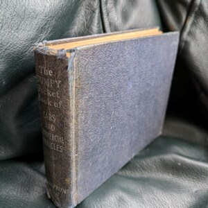 Puede incluir: Un libro azul desgastado titulado "The Dumpy Pocket Book of Cars and Commercial Vehicles".