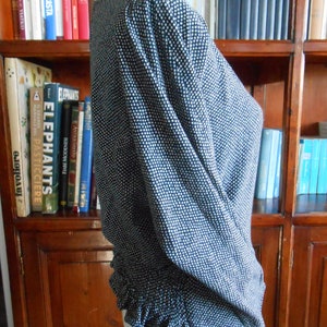 Peut inclure: Un chemisier à pois noirs et blancs avec un ourlet à volants. Le chemisier a un col rond et des manches longues.