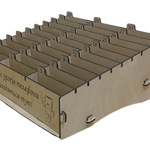 Puede incluir: Una caja de madera con 30 ranuras numeradas para guardar objetos. La caja tiene un letrero que dice "Під час уроків телефони знаходяться тут!" que se traduce como "¡Durante las clases, los teléfonos están aquí!"