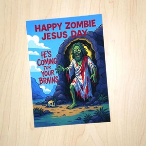 May include: A novelty greeting card featuring the words "HAPPY ZOMBIE JESUS DAY" and "HE'S COMING FOR YOUR BRAINS." The image shows a zombie Jesus figure emerging from a cave, with a skull in the foreground.