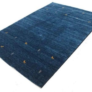 May include: A blue rug with a subtle pattern of small white branches and orange deer. The rug has a gradient effect, with a darker blue colour at the top and a lighter blue colour at the bottom.