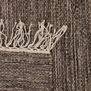 May include: A brown and beige woven rug with fringe on the edges.