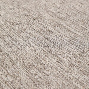 May include: Close-up of a beige rug with a textured woven pattern.