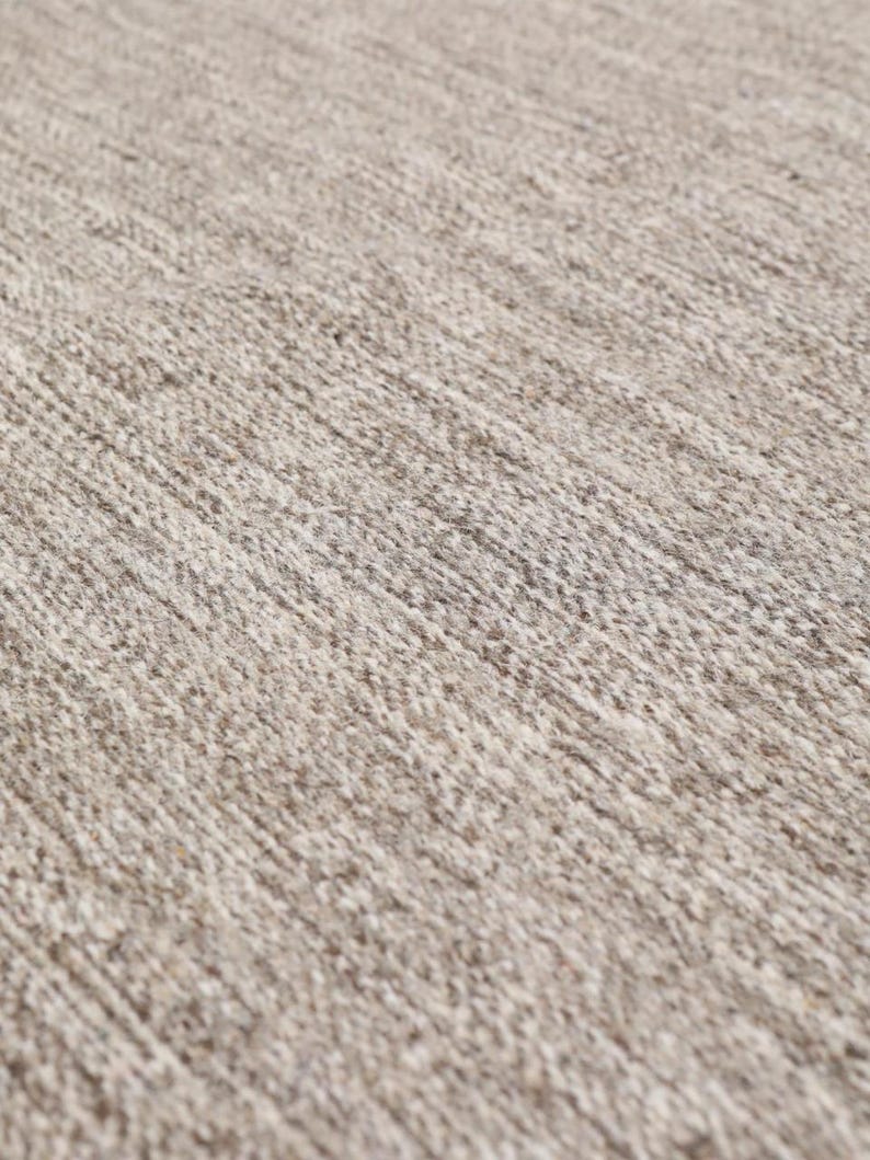 May include: Close-up of a beige rug with a textured woven pattern.