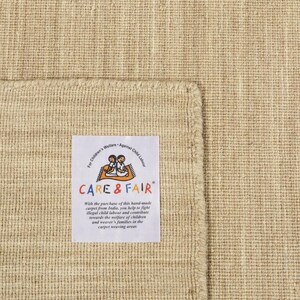 May include: A beige hand-woven rug with a label that reads "Children's Welfare Against Child Labour CARE & FAIR" and explains that the purchase of the rug helps fight illegal child labour in India.