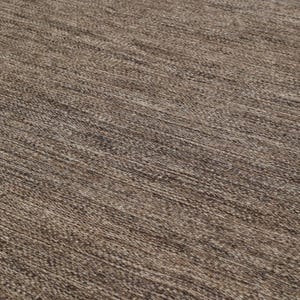 May include: Close-up of a brown woven rug with a subtle texture. The rug has a natural, earthy tone and a slightly rough surface.