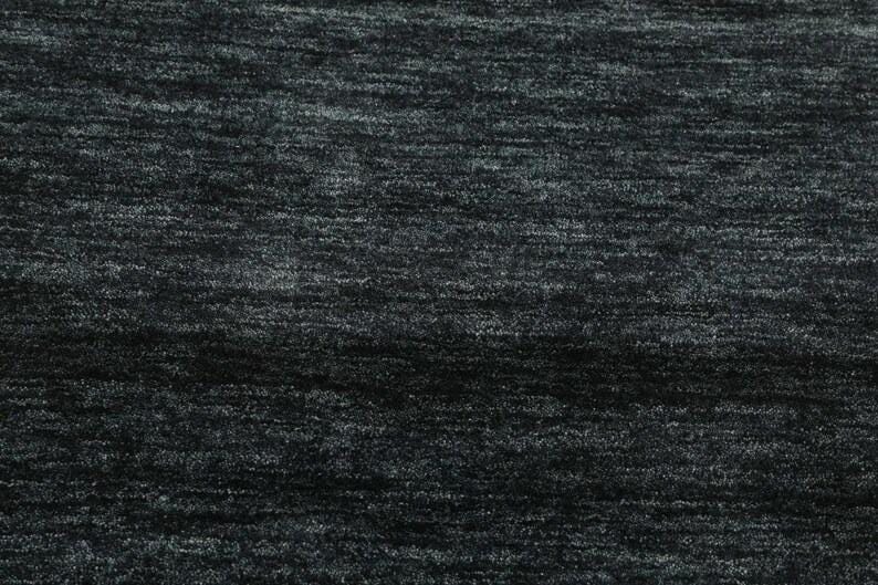May include: A close-up of a dark gray textured fabric with a subtle sheen. The fabric has a slightly uneven surface, creating a subtle pattern.