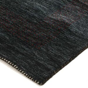 May include: Close-up of the edge of a dark gray rug with a subtle pattern. The rug has a white stitched border.