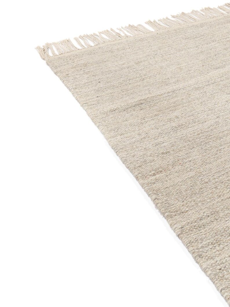 May include: A beige woven rug with fringe on the edges.