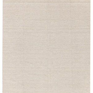 May include: A plain, off-white woven rug with a fringed edge.