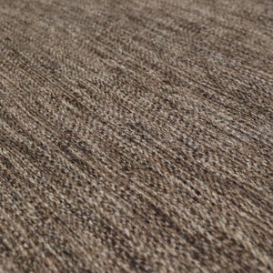 May include: Close-up of a brown and beige woven rug with a textured surface.