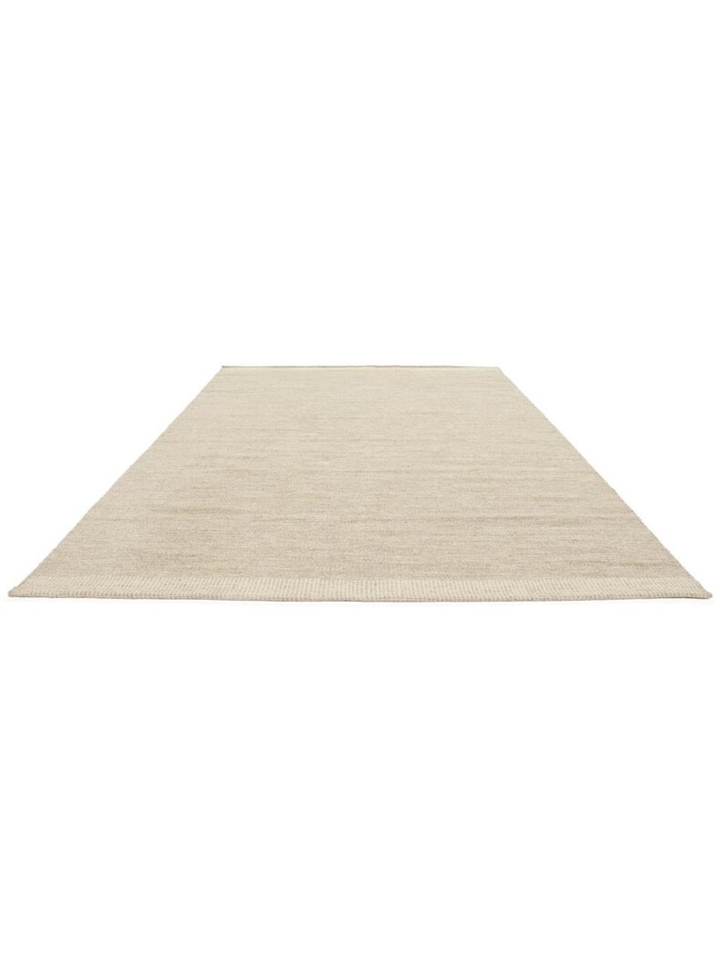 K&ouml;nnte beinhalten: Ein rechteckiger beigefarbener Teppich mit einer dezenten Textur. Der Teppich hat ein schlichtes, modernes Design und ist aus einem nat&uuml;rlichen Material gefertigt.