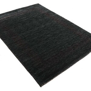 May include: A dark gray area rug with a subtle, textured pattern. The rug has a slightly faded look, giving it a vintage feel.