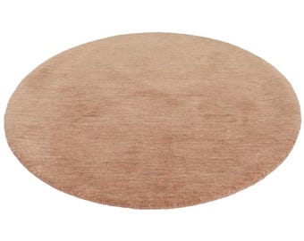 Puede incluir: Una alfombra redonda de color rosa claro con una textura suave y peluda.