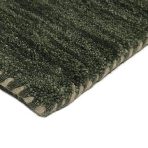 May include: Close-up of a green rug with a textured, ribbed design. The rug has a darker green color with lighter green and beige accents along the edge. The rug's corner is visible against a white background.