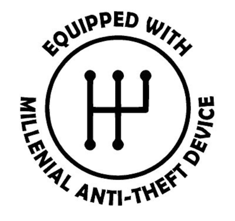 May include: A black and white graphic with the text "Equipped With Millennial Anti-Theft Device" encircling a gear shift symbol. The design is circular and bold, suitable for stickers or apparel.