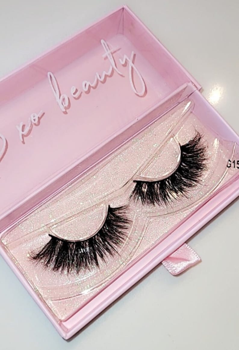 May include: A pair of false eyelashes in a pink box with glitter. The box has the text "xo beauty" on the top.