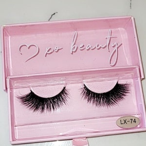 May include: A pink box with a heart and the text "xo beauty" on the top. The box contains two pairs of black false eyelashes. The box also has a label with the text "LX-74".