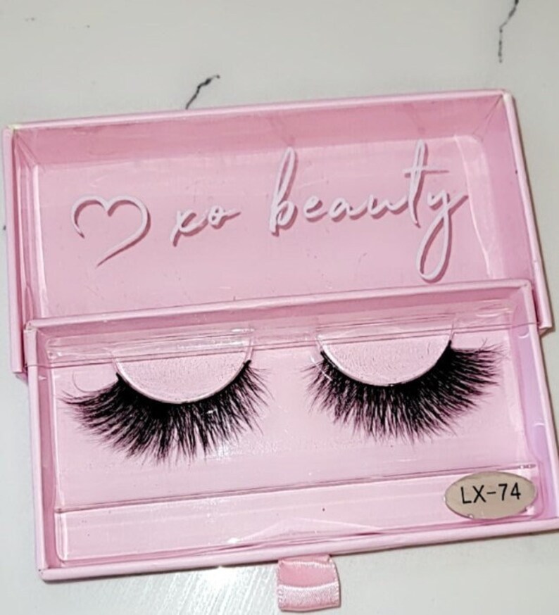 May include: A pink box with a heart and the text "xo beauty" on the top. The box contains two pairs of black false eyelashes. The box also has a label with the text "LX-74".