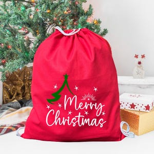 May include: Red drawstring bag with a white "Merry Christmas" design and a green Christmas tree graphic.