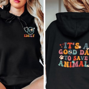 May include: Black hooded sweatshirt with a rainbow graphic that says "It's a good day to save animals" on the back and a stethoscope with a paw print and the name "Emily" on the front.
