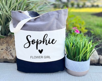 May include: A white canvas tote bag with a gray and black stripe design. The bag has the name "Sophie" printed on it in black cursive font with a small black heart and the words "Flower Girl" printed below.