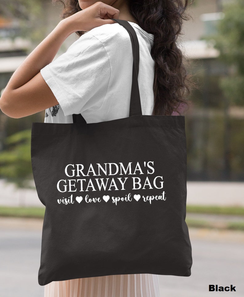 Pu&ograve; includere: Borsa tote nera con testo bianco che dice "Grandma's Getaway Bag visit love spoil repeat".
