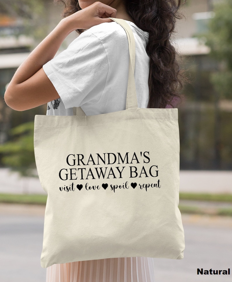 Pu&ograve; includere: Una borsa tote in tela naturale con il testo "Grandma's Getaway Bag" e la frase "visit love spoil repeat" con cuori tra le parole.