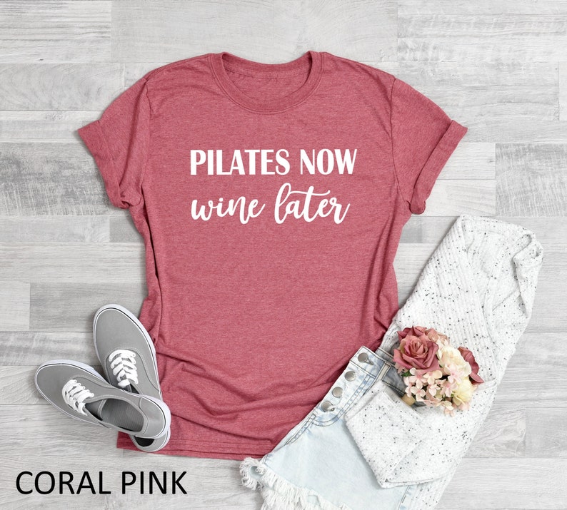 K&ouml;nnte beinhalten: Korallenrosa T-Shirt mit dem Text "Pilates Now Wine Later" in wei&szlig;en Buchstaben.