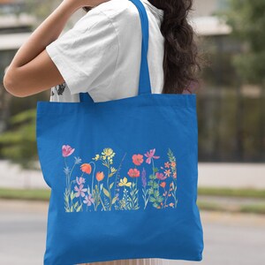 Może przedstawiać: Torba typu tote w kolorze kr&oacute;lewskim błękitu z kolorowym wzorem kwiatowym. Torba ma dwa długie uchwyty i jest wykonana z wytrzymałego materiału canvas.