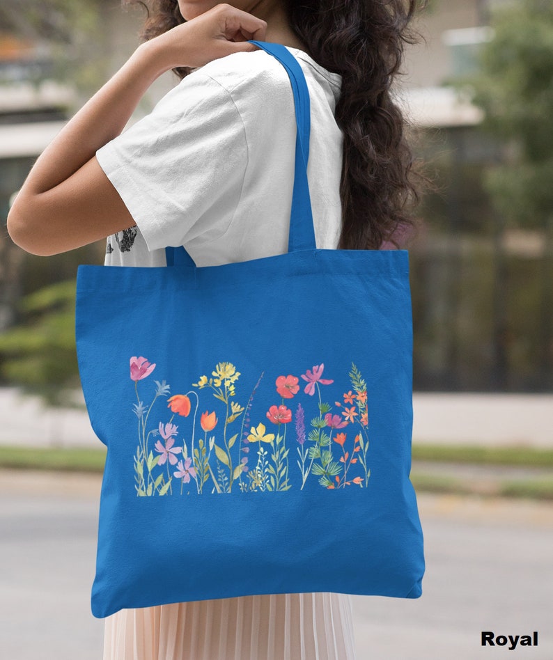 Może przedstawiać: Torba typu tote w kolorze kr&oacute;lewskim błękitu z kolorowym wzorem kwiatowym. Torba ma dwa długie uchwyty i jest wykonana z wytrzymałego materiału canvas.