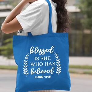 May include: A royal blue tote bag with white text that reads "blessed is she who has believed" and "LUKE 1:45".