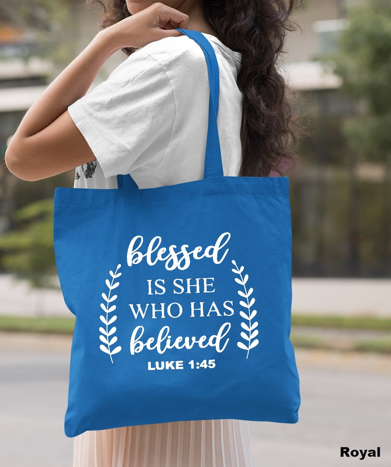 May include: A royal blue tote bag with white text that reads "blessed is she who has believed" and "LUKE 1:45".