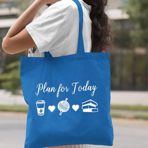 May include: A royal blue tote bag with white text that reads "Plan for Today". The bag features a coffee cup, yarn, and books with hearts in between each item.