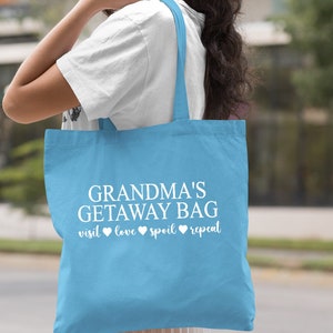 Pu&ograve; includere: Borsa tote blu chiaro con il testo "Grandma's Getaway Bag visit love spoil repeat" in bianco.