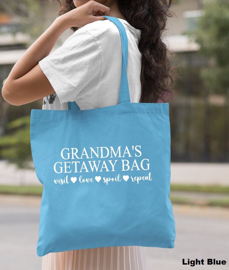 Pu&ograve; includere: Borsa tote blu chiaro con il testo "Grandma's Getaway Bag visit love spoil repeat" in bianco.